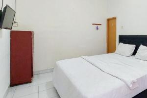 une chambre avec un lit et une télévision à écran plat dans l'établissement Pondok Gede Dkost Syariah Mitra RedDoorz, à Bekasi