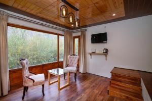 a living room with two chairs and a table and a window at Thiksay Organic Resort in Ranbirpura