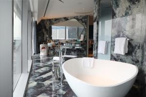 La salle de bains est pourvue d'une grande baignoire et d'un grand miroir. dans l'établissement W XIAN Hotel, à Xi'an