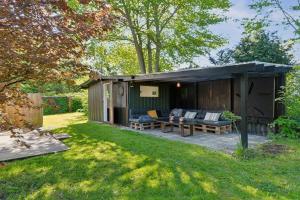 a shed with a couch and chairs in a yard at Spacious Summer House With Pool in Vejby