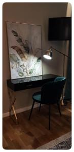 un escritorio y una silla en una habitación con una pintura en Elania Residence en Târgu Jiu