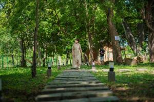 une femme qui marche sur un chemin de pierre dans un parc dans l'établissement Tranquil Wild, à Tanamalwila