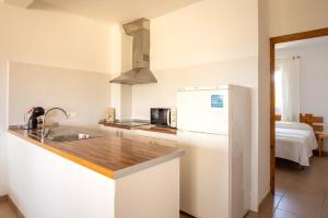 La cuisine blanche est équipée d'un évier et d'un réfrigérateur. dans l'établissement Apartamentos Verde Mar, à Es Pujols