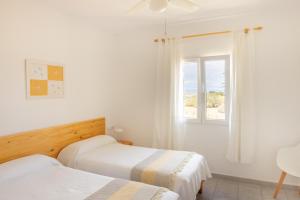 - 2 lits dans une chambre avec fenêtre dans l'établissement Apartamentos Verde Mar, à Es Pujols