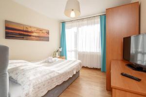 a bedroom with a bed and a flat screen tv at Willa Przy Plaży in Pogorzelica
