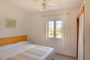 a white bedroom with a bed and a window at Apartamentos Verde Mar in Es Pujols