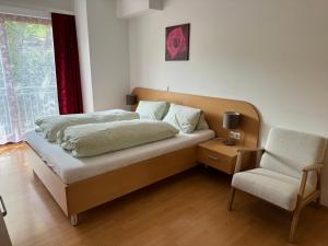 sypialnia z łóżkiem, krzesłem i oknem w obiekcie Lindenhof Deutsch w mieście Bad Tatzmannsdorf