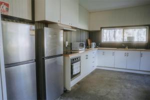 a kitchen with white cabinets and stainless steel appliances at Tiny House 18 at Grampians Edge in Dadswells Bridge