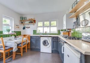 eine Küche mit einer Waschmaschine und einem Tisch mit Stühlen in der Unterkunft St. Brides Cottage in Saundersfoot