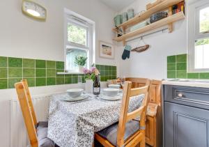 サンダースフットにあるSt. Brides Cottageの緑のタイル張りのキッチン(テーブル、椅子付)
