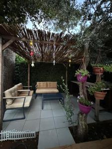 a patio with a couch and chairs under a pergola at Villaras Garden özel havuzlu eşyalı in Altınkum