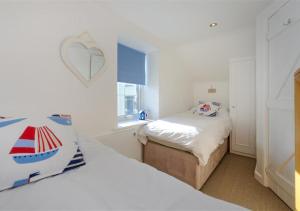 a small bedroom with two beds and a window at Jennys Cottage in Abersoch