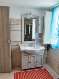 ein Badezimmer mit einem weißen Waschbecken und einem Spiegel in der Unterkunft Da Tziu Efisiu - IUN : R2417 in Baratili San Pietro