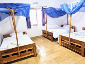 3 camas en una habitación con sombrillas azules en STC.SAFARI LODGE, en Oldeani