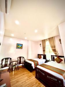 Habitación de hotel con 2 camas, mesa y sillas en TRƯỜNG GIANG HOTEL Móng Cái en Móng Cái