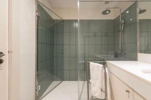 a glass shower in a bathroom with a sink at Marias River Apartment in Porto