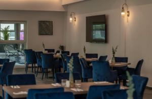 une salle à manger avec des tables en bois et des chaises bleues dans l'établissement Srebrna Wydma Resort, à Dąbki