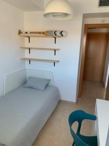 a small bedroom with a bed and a blue chair at Apartamento de estilo mediterráneo in Miami Platja
