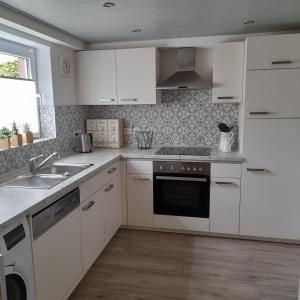 a kitchen with white cabinets and a sink at Ferienwohnung am Fussweg zur Therme in Bad Rodach