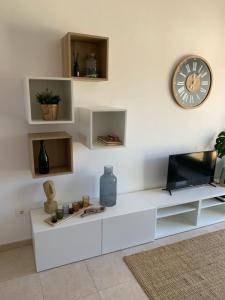 sala de estar con TV y reloj en la pared en Apartamento de estilo mediterráneo, en Miami Platja