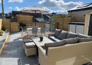 a patio with a couch and a table and an umbrella at Enfield House in Saundersfoot