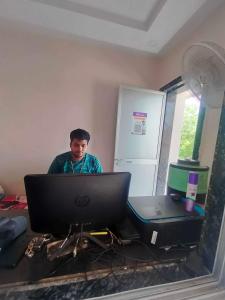 un hombre sentado frente a un ordenador portátil en OYO 81285 Hotel Chanda en Madhubani