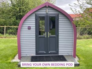 une dépendance grise et violette avec une porte dans une cour dans l'établissement Belle Vista Glamping & Camping, à York