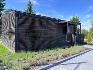 una pequeña casa de madera con un exterior negro en Lawendowe Domki Latoszyn-Zdrój Domek Hygge, en Latoszyn