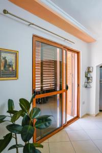 une porte coulissante en verre dans une pièce avec une plante dans l'établissement Tirana Centre Lions Gate 1 Apartment, à Tirana