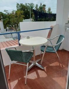 uma mesa branca e 2 cadeiras numa varanda em "CASA RAMOS" Oura Nightlife Street Guest House em Albufeira