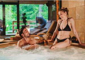 un homme et une femme assis dans un bain à remous dans l'établissement Hotel Tri Studničky - Adult friendly, à Demänovská Dolina