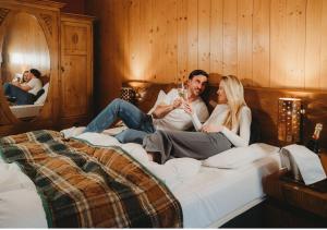 a man and a woman sitting on a bed at Hotel Tri Studničky - Adult friendly in Belá