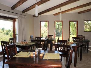 a dining room with tables and chairs and windows at Midlands Forest Lodge in Balgowan