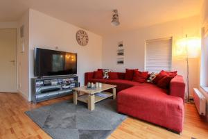 a living room with a red couch and a tv at KG - Villa Dijkhuys 9 in Opperdoes +1 photo