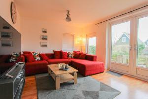 a living room with a red couch and a table at KG - Villa Dijkhuys 9 in Opperdoes