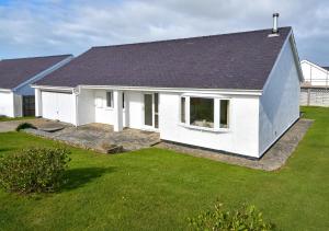a white house with a black roof and a yard at 15 Lon Cernyw in Abersoch