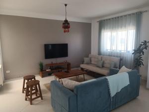 sala de estar con sofá azul y TV en Superbe étage de villa vue sur mer en Nabeul