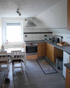 cocina con mesa, fogones y ventana en Ferienwohnung Hammerwaldblick im Dachgeschoss, en Selb