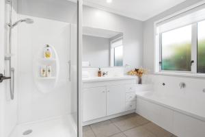 a white bathroom with a tub and a sink at Stylish warm house in north Hamilton in Hamilton +23 photos