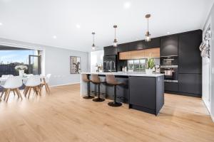a kitchen with black cabinets and a table and chairs at Stylish warm house in north Hamilton in Hamilton