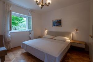 a bedroom with a bed with a chandelier and a window at Apartments Mirella in Novigrad Istria