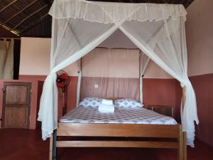 a bed with a canopy in a room at Auberge Le Lagon in Nosy Be