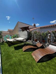 a garden with chairs and an umbrella on the grass at l'evasion ,maison de ville jacuzzi couchages x6 in Le Grau-du-Roi