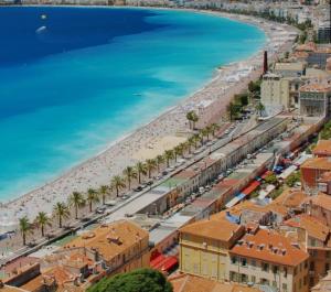 - une vue aérienne sur une plage bordée de palmiers et de bâtiments dans l'établissement Duplex quatre pièces - une chambre bébé, à Nice