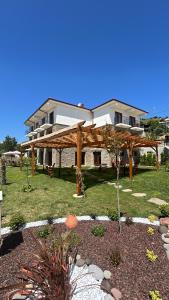 a house with a wooden pergola in a yard at TERRA GAİA Hotel in Gokceada Town