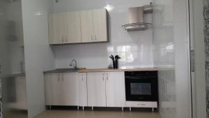 a kitchen with white cabinets and a black oven at Monte-Kristo Hotel in Kamianets-Podilskyi
