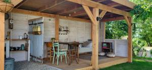 a wooden pergola with a table and chairs in a backyard at Petit a Petit - gypsy wagons and Bell tents in the Bourgogne in Saisy
