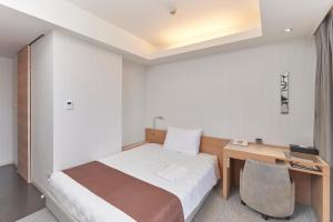 Habitación de hotel con cama y escritorio en Naha Tokyu REI Hotel, en Naha