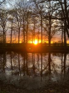 a sunset in a field with trees and water at Rouge Maison in Bois-Normand-près-Lyre