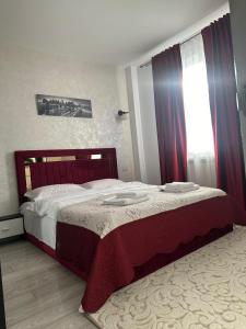 a bedroom with a large bed with red curtains at Apartament Rezidențial in Suceava